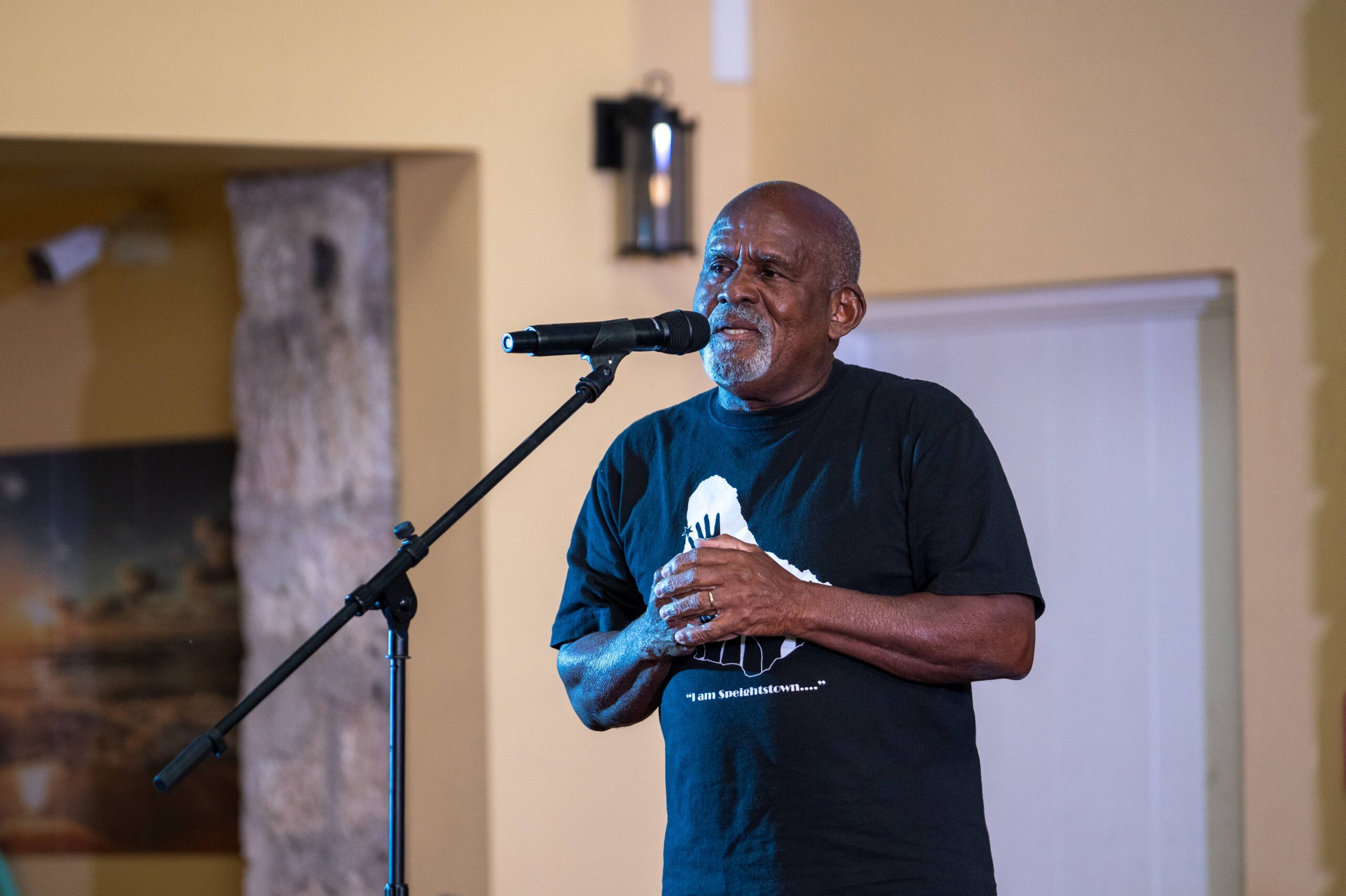 Older man speaking into a microphone on stage